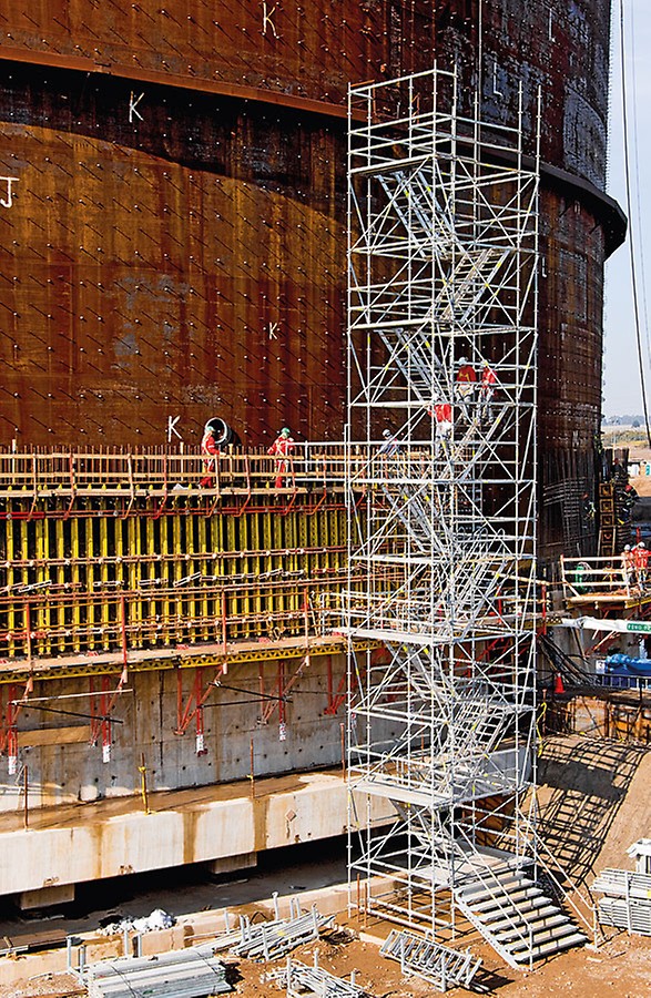 Stair tower with twin staircase units for the construction of a liquid gas tank. Guardrails mounted on the outer and middle stringers provide safe passage.