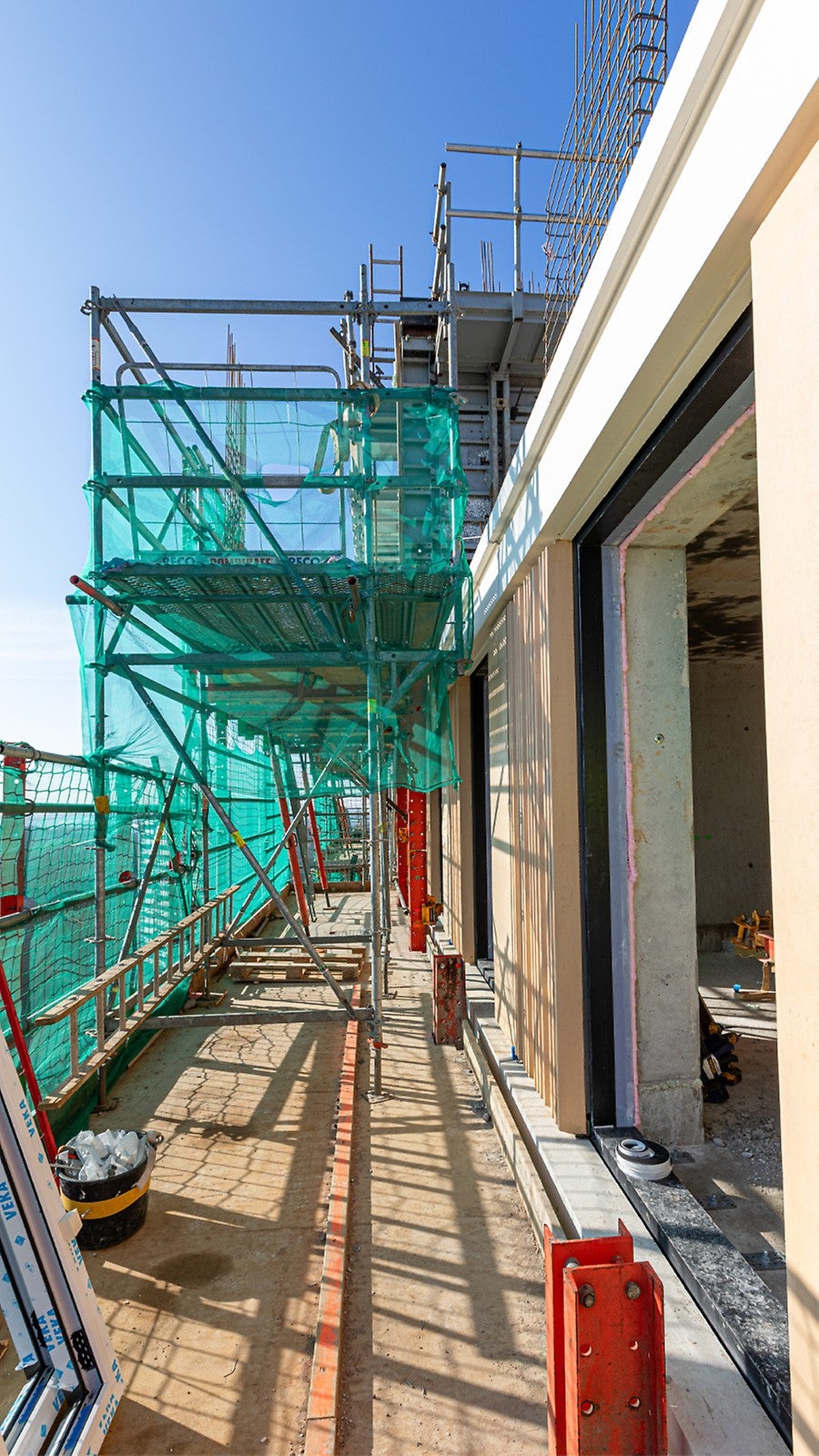 Dankzij de PERI UP Omloopsteiger kan er vanuit de klimsteiger een verdieping hoger naar de naastgelegen steiger op de bovenste vloer gelopen worden.