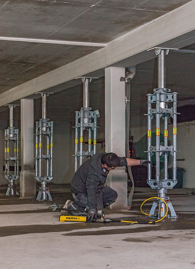 Worker who sets the PERI UP lowering spindle with a hydraulic unit.