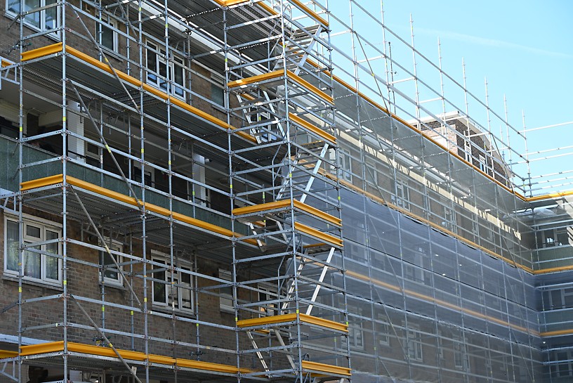 Facade access wraps around Treadgold House. Metal scaffolding wraps around the side of a multi-storey residential building.