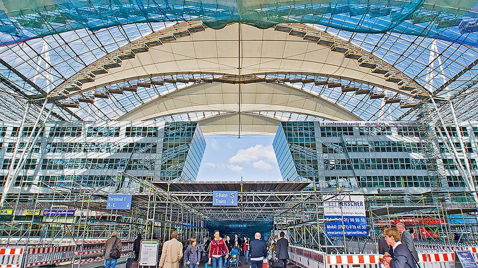 慕尼黑机场顶棚翻修 - 满足顶级安全标准 Forum roof Munich Airport, Germany - Replacing the membrane was carried out during ongoing daily airport operations. Maximum safety was ensured through a large-area protective roof construction installed at the height of the forum area in addition to the safety netting underneath the scaffolded roof sections.