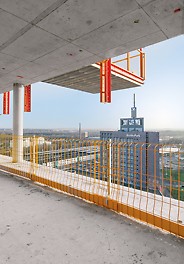 Efficient formwork and safety concept by PERI. View from one floor of the shell structure, where the yellow PERI PROKIT side mesh barrier has been installed and where the MP landing platform from the floor above can be seen.