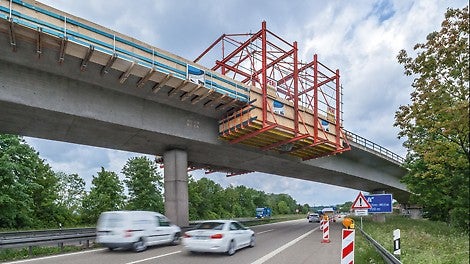 Um die Gesimskappenschalung ohne Sperrung und ohne Gefährdung der Kreuzungsbereiche montieren und demontieren zu können, diente ein 12 m langer Montagewagen aus VARIOKIT Bauteilen als Arbeitsbühne.