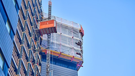 Woontoren in aanbouw, goederenlift en klimsysteem aan de gevel.