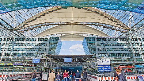 Forum roof Munich Airport, Germany - Replacing the membrane was carried out during ongoing daily airport operations. Maximum safety was ensured through a large-area protective roof construction installed at the height of the forum area in addition to the safety netting underneath the scaffolded roof sections.
