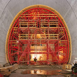 Tunnel Umfahrung Flüelen, Schweiz - Die Anstütz- und Umsetzkonstruktion wurde aus dem PERI Tunnel-Riegel-System gebildet, das sich dem erforderlichen Querschnitt exakt anpassen lässt. Die komplette Schalungseinheit ließ sich mit einem bauseitigen Zuggerät auf Schienen von Abschnitt zu Abschnitt bewegen. Das Ein- und Ausschalen erfolgte aus wirtschaftlichen Gründen mechanisch.