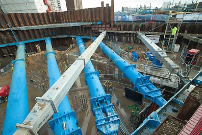Multiple big blue pipes being installed at a construction site, ready to carry water or something else.