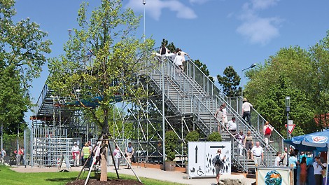 PERI UP Rosett Public Stair Solution for a trade fair: stairway leading to a pedestrian bridge which crosses a multi-lane road.