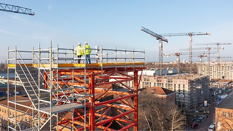 Gerüstbauer auf einer 30 Meter hohen Aussichtsplattform blicken über die Baustelle der Modellstadt 'Das neue Gartenfeld' in Berlin.