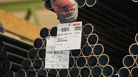 Supply Chain Sourcing at PERI The image shows a stapel of tubes with a sign that describes it as material in a PERI stockyard.