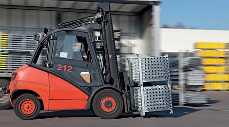 A forklift operator moves scaffolding materials to the job site.