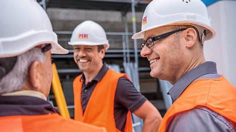 Drei PERI Mitarbeiter reden miteinander.
