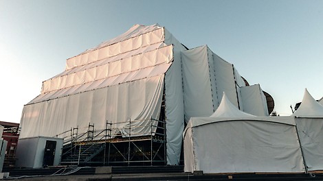 Белый тент, который закрывает тыльную и боковые стороны сцены, крепится к конструкции через люверсы. Так как конструкция в завершенном виде представляет собой практически замкнутый объём, то ветровые нагрузки распределяются по всей поверхности тента более равномерно.