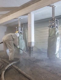 Refurbishment of the reinforced concrete supports Worker refurbishes a reinforced concrete support with the SPCC dry-mix shotcreting procedure while PERI UP heavy-duty props provide support for the slab.