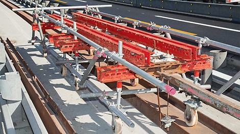 Il carrello traslabile VARIOKIT, a cui è stata appesa un&#039;impalcatura PERI UP con l&#039;ausilio di tiranti DW 15, avanzava all&#039;interno dei guardrail esistenti