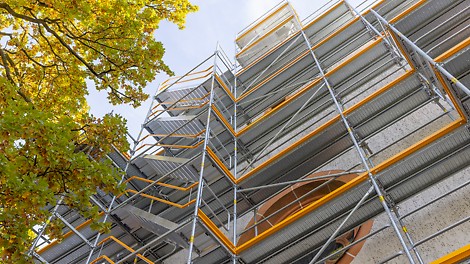 PERI UP Safety Paket Die vorlaufende Geländermontage der PERI UP Treppe in 67 cm Breite an einem Gebäude.