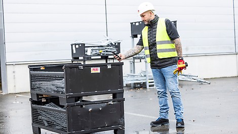 Mobile Logistics Scan QR Code Person scannt den QR Code an einer Gitterbox mit dem Smartphone