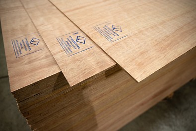 Stacked wooden boards for flooring, featuring a logo signifying their certified status.