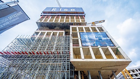 Ansicht von unten auf das PANDION Officehome Rise während der Konstruktion. Das Gebäude ist teilweise von Gerüsten umschlossen.