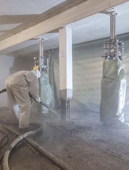 Worker refurbishes a reinforced concrete support with the SPCC dry-mix shotcreting procedure while PERI UP heavy-duty props provide support for the slab.