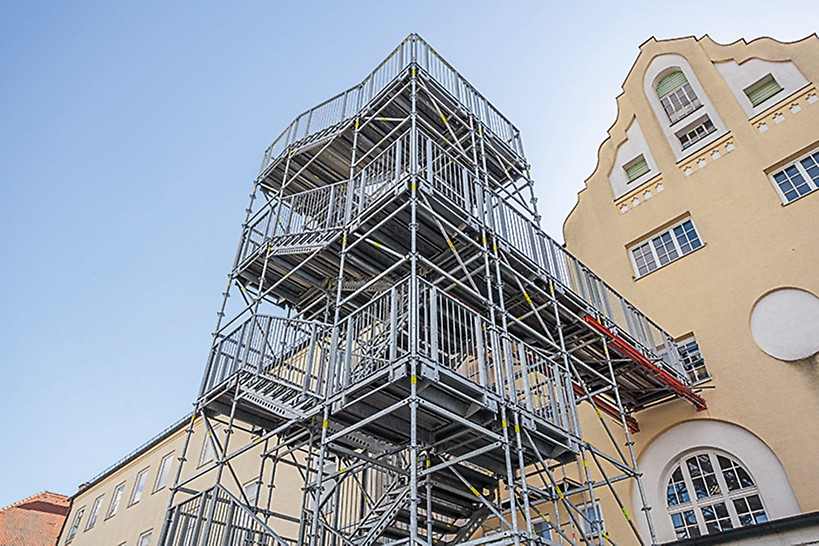 Durante trabalhos de reconstrução, esta torre de escada de 14m serve como saída de emergência. Componentes do sistema VARIOKIT suportam a passagem para o edifício.