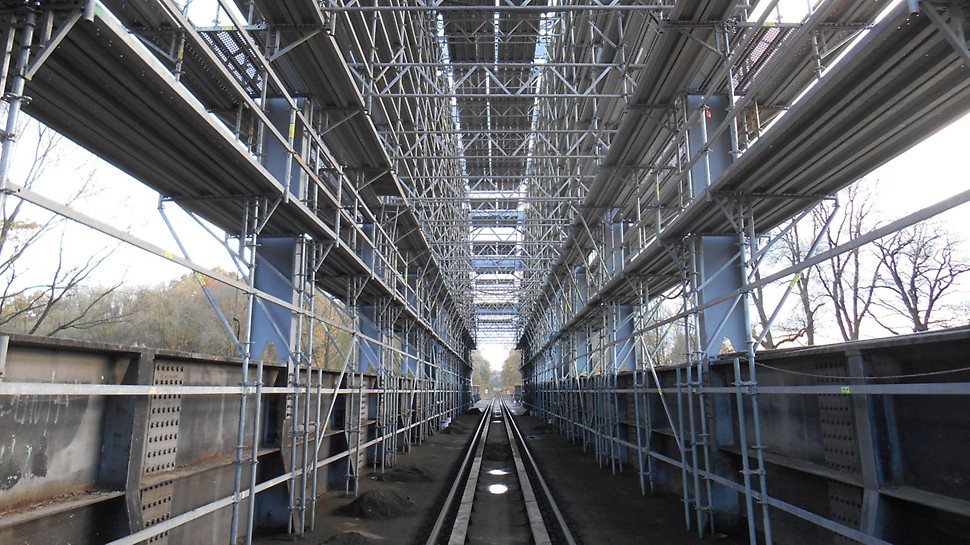 Železniční vlečka Biocel Paskov: Přizpůsobené modulové lešení PERI UP Rosett Flex pro oblouky a výztuhy vrchní části mostu se zachováním průjezdného profilu trati.