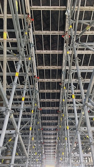 Kikvorsperspectief van de SKYDECK vloerbekisting boven de inkomhal op 6m50 hoogte, ondersteund door een PERI UP steiger met speciaal door PERI ontwikkelde valkopsystemen.   