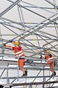 Arbeiter verschieben ein Bindersegment des PERI Wetterschutzdaches auf Rollen ohne maschinelle Hilfe.