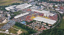 Luftaufnahme vom Firmengelände der PERI GmbH in Weißenhorn. Zwischen den großen Gebäuden sieht man die roten und gelben Schalungs- und Gerüstsysteme, die auf den Lagerflächen gestapelt wurden.