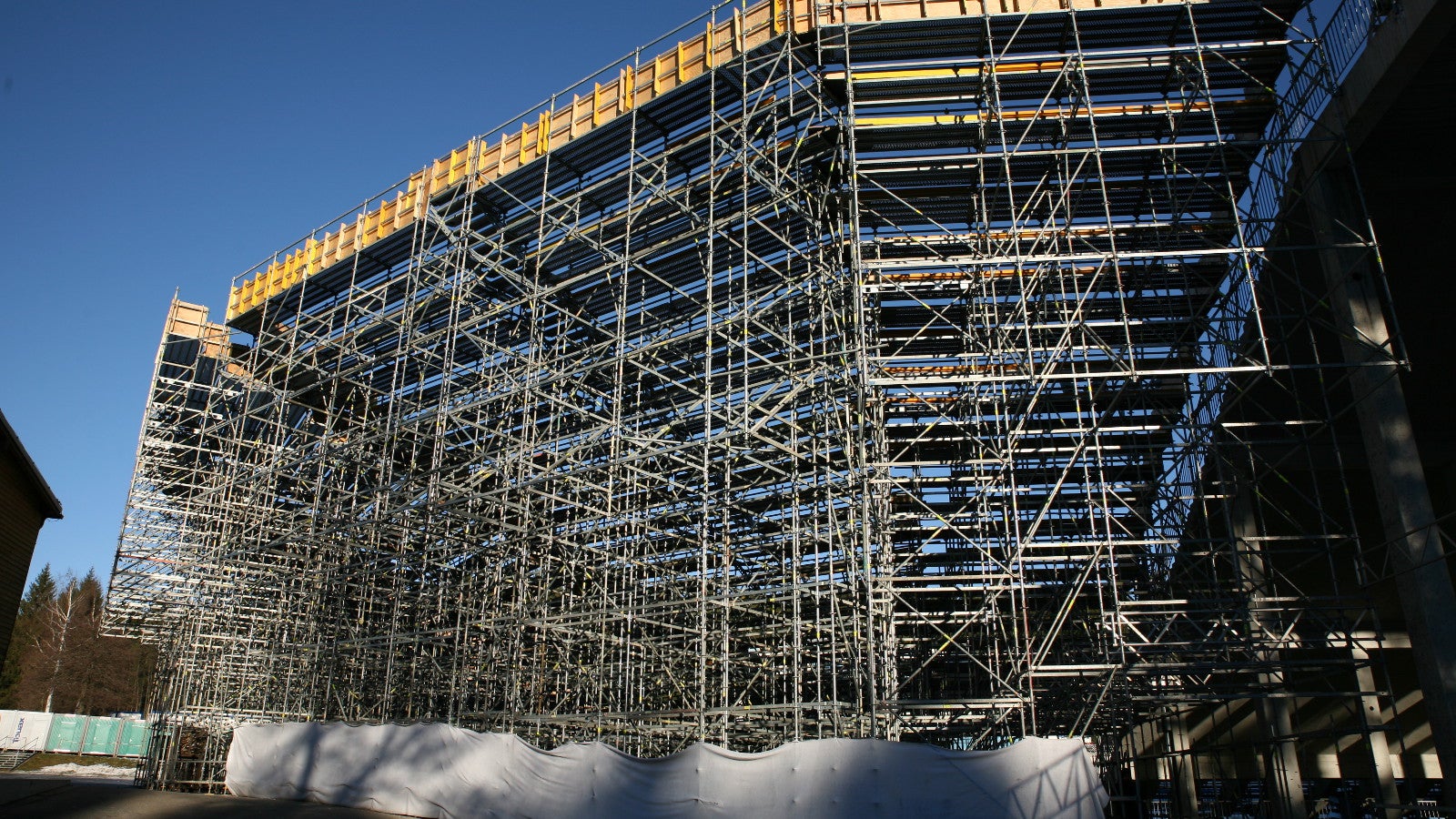 Zadní strana konstrukce lešení vytvářející doplnění stávající tribuny na stadionu.