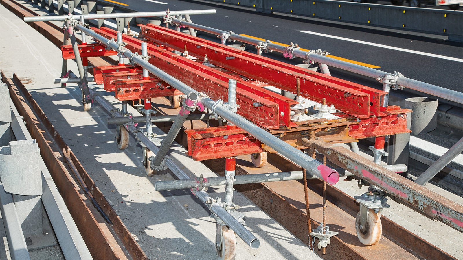 Il carrello traslabile VARIOKIT, a cui è stata appesa un'impalcatura PERI UP con l'ausilio di tiranti DW 15, avanzava all'interno dei guardrail esistenti