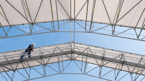 The proven PERI UP Rosett Flex LGS weather protection roof can now be supplemented with walkways for safe access. Suspended from the bottom chord, the brackets form – together with proven UDI decking and standard guardrails – safe walkways along the truss girder. Pre assembly takes place on the ground before the crane lifts the complete roof segment into position.