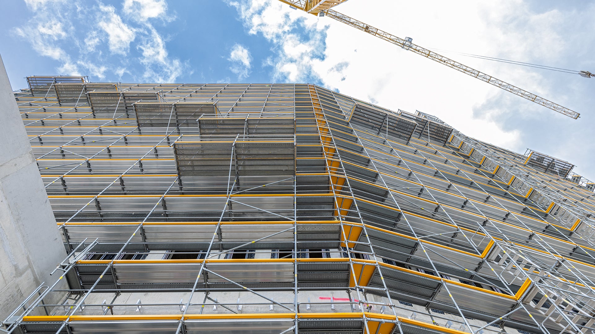 In das PERI UP Fassadengerüst integrierte Absetzbühnen kragen jeweils 1,50 m nach außen aus und dienen zur Andienung, Lagerung und Vormontage der Fassadenelemente.