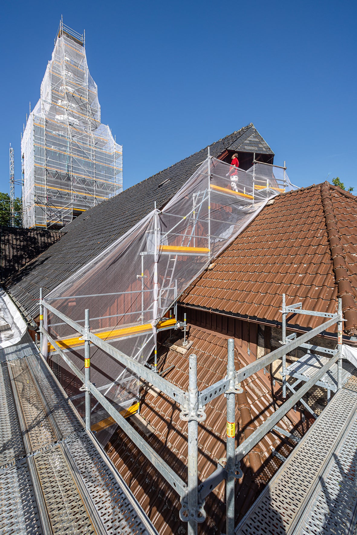 Kirchenschiff und Kirchenturm umschmiegt ein PERI UP Arbeits- und Schutzgerüst – mit großzügigen und stolperfrei ausgeführten Arbeitsebenen zur unproblematischen und fachgerechten Durchführung