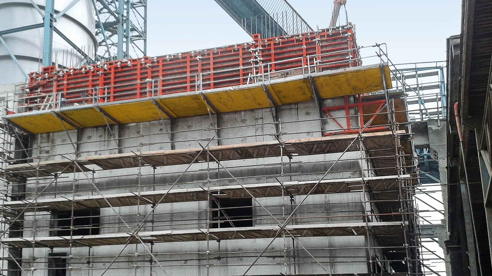 Stavba medzizásobníku slinku má obdĺžnikový pôdorys a rástla postupne od základov osadených na širokopriemerových pilótach cez podzemné podlažie až po nadzemné podlažie do výšky 23,85 m, kde je šikmá doska pod dopravníkom umiestnená do šikmých stien