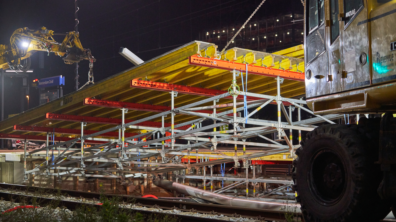 Elk perronelement bestaat uit gele VT20 Alpha 3S dragers en rode stalen SRU gordingen. Dankzij de hijsluiken kan de perronconstructie snel en eenvoudig op het onderstel (PERI UP steigersysteem) geplaatst worden.