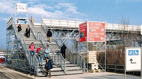 Lösung für eine Messe: Treppe zu einer Fußgängerbrücke über eine mehrspurige Straße mit getrennten Bereichen für den Auf- und Abgang.