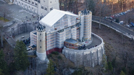 Der östliche Torbau von Schloss Neuschwanstein war mit PERI UP Fassadengerüst für komplexe Gebäudestrukturen komplett eingerüstet, ein temporäres Wetterschutzdach überspannt den Zugang zum Schloss.<br/>