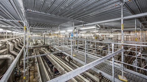The PERI UP scaffold level at a height of 5 m reliably separates the production line of the bottling plant from the construction work on the roof structure.