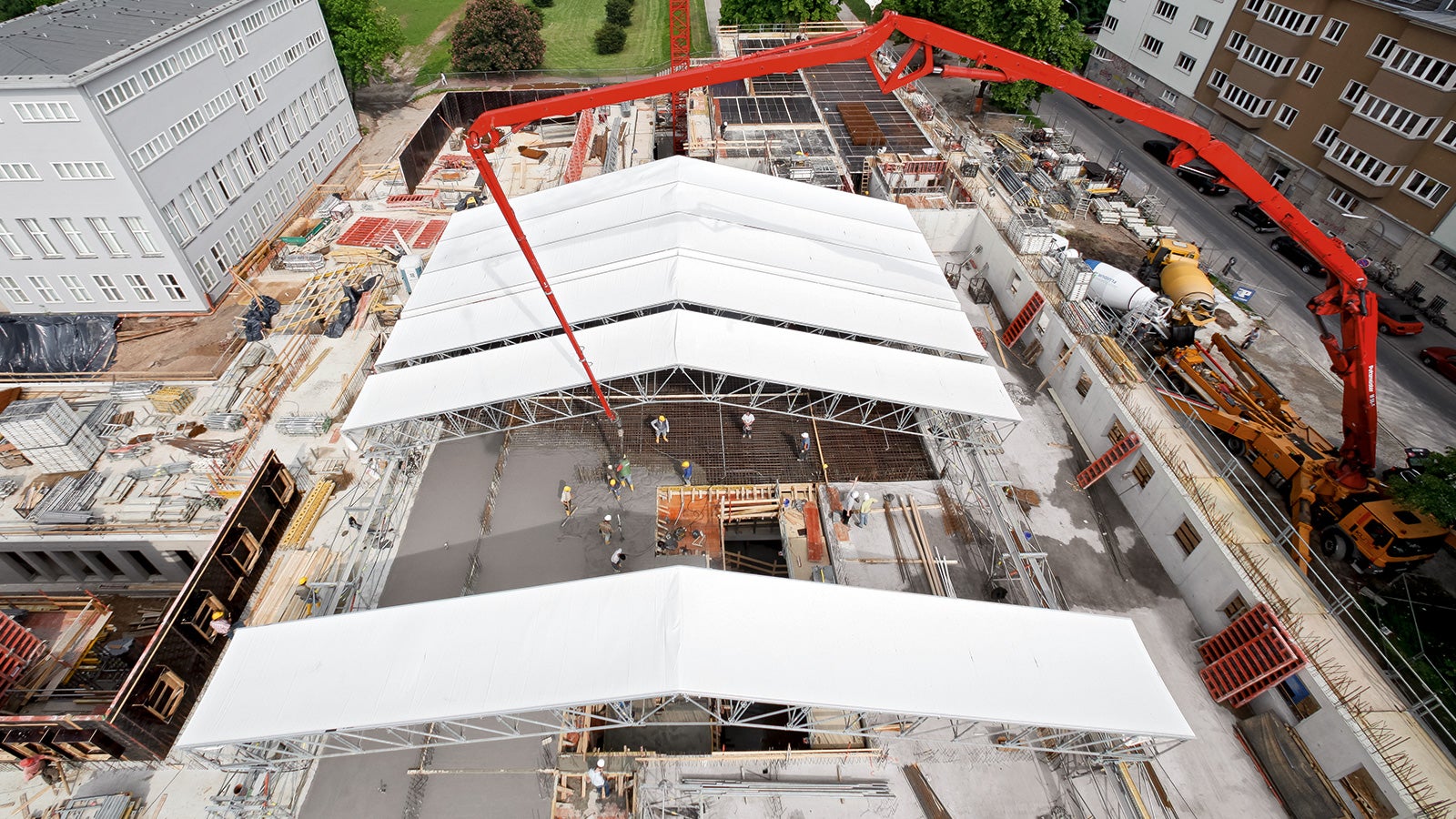 During shell construction, the PERI UP weather-protection roof offers temporary protection against rain, snow or heat. The elements can be moved by hand. In the motor-operated version, the individual segments of roof sheeting can be easily coiled up or uncoiled; a heated version reduces the snow load in winter.