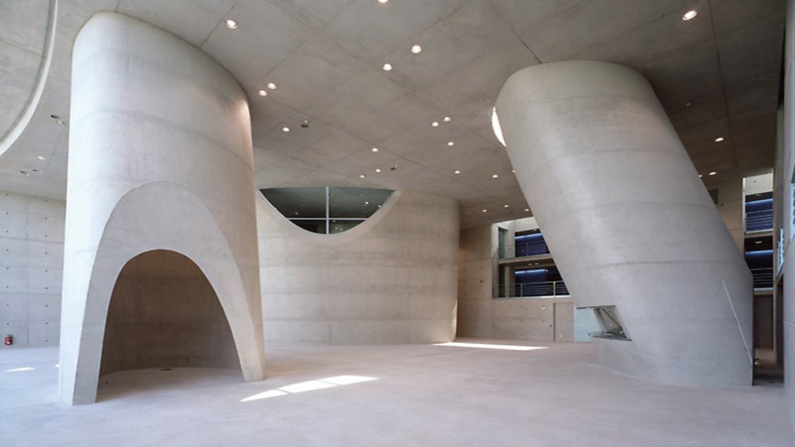 The Galileo Satellite Control Centre in Oberpfaffenhofen was designed as a monolithic structure by the architectural offices Schultes Frank Architekten in Berlin and Aichner Kazzer Architekten in Munich. The exterior walls, cores and the roofing of the inner courtyard of the laboratory and research building have a seamless exposed concrete look. In the inner courtyard, three inclined, elliptical exposed concrete towers symbolise oversized telescopes observing satellites in space.