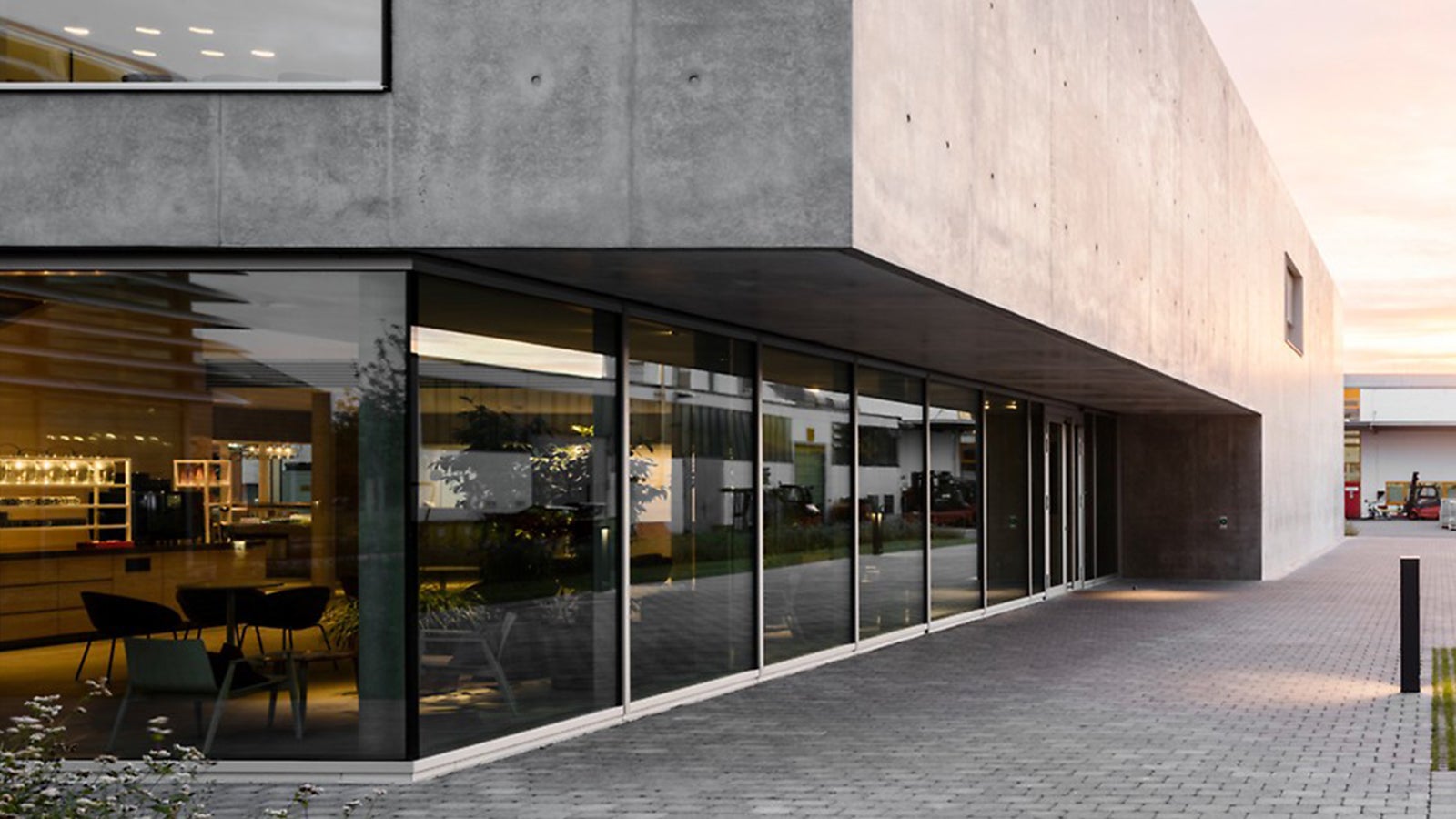 The canteen at the PERI headquarters in Weissenhorn was designed by the daughter of the company founder, architect Nathalie Schwörer, in collaboration with architects Mühlich, Fink &amp; Partner. Two cubes of almost equal size create a bright and open atmosphere. The southern cube made of exposed concrete houses the main entrance, the foyer with coffee bar and the kitchen. Glass is the dominant feature in the northern cube. This is where most of the seating is located, practically flowing into the outdoor area. Photo: Hiepler- Brunier Fotostudio esw