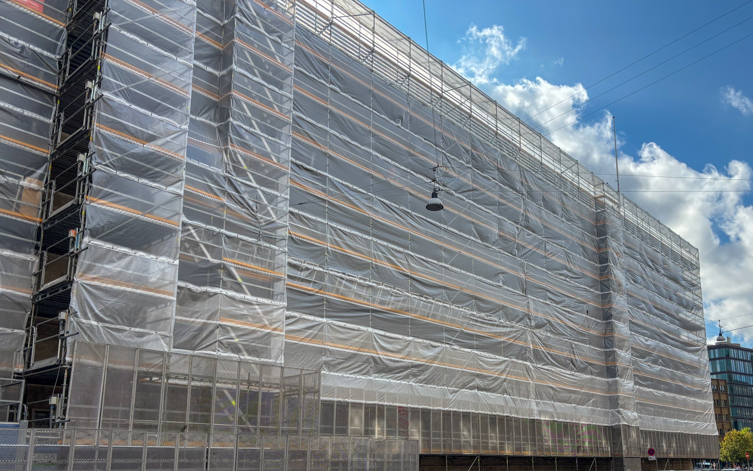 For at sikre mere stabile arbejdsforhold er der monteret klimaskærm på stilladset. <br/>Det gør det muligt for murerne at arbejde i tørvejr og mindsker vejrets indflydelse på fremdriften. Klimaskærmen bidrager til bedre kontinuitet i arbejdet og er en vigtig del af løsningen på et projekt, der strækker sig over flere år og årstider.