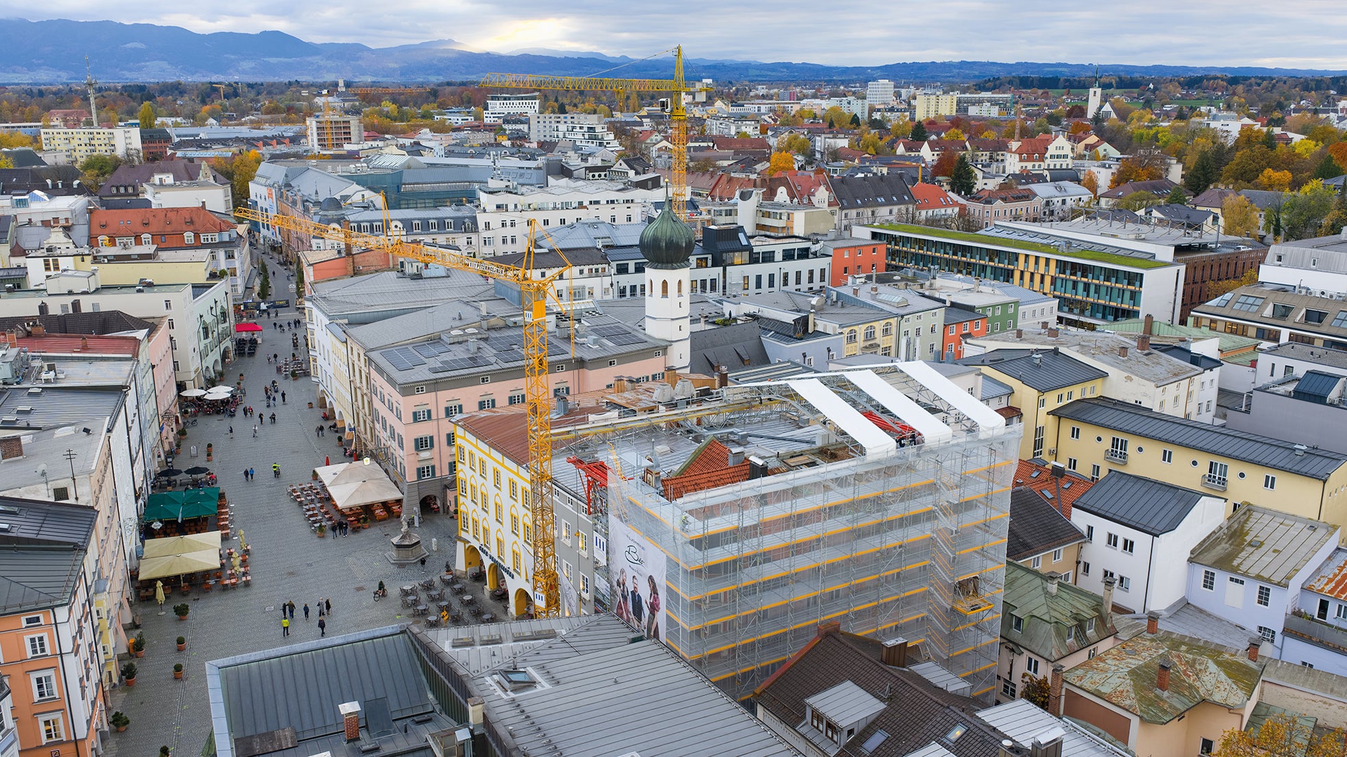 Mitten in Rosenheim wird das denkmalgeschützte Gebäude am Max-Josefs-Platz saniert. PERI kombiniert Fassadengerüst, Überbrückungen und Wetterschutzdach zu einer passgenauen Lösung für die besondere Innenstadtlage.