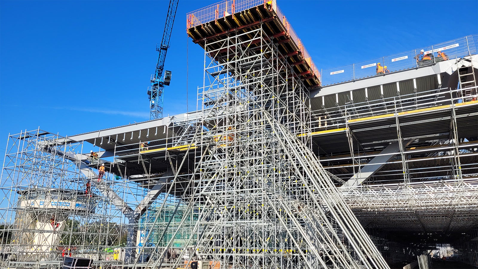 Platforma VARIOKIT na rusztowaniu podporowym PERI UP FLEX na kontener do prefabrykacji blachy zapewniająca bezpieczeństwo na wysokości 14 m.