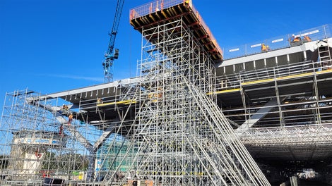 Platforma VARIOKIT na rusztowaniu podporowym PERI UP FLEX na kontener do prefabrykacji blachy zapewniająca bezpieczeństwo na wysokości 14 m.