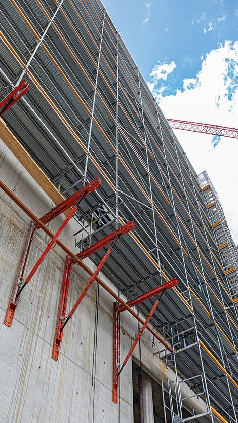 Metrisch kombinierbar: Tragfähige Konsolen auf Basis von VARIOKIT Kernbauteilen unterstützen das PERI UP Fassadengerüst dort, wo der Untergrund nicht genügend tragfähig ist oder darunter liegende Bereiche als Verkehrsfläche freizuhalten sind.