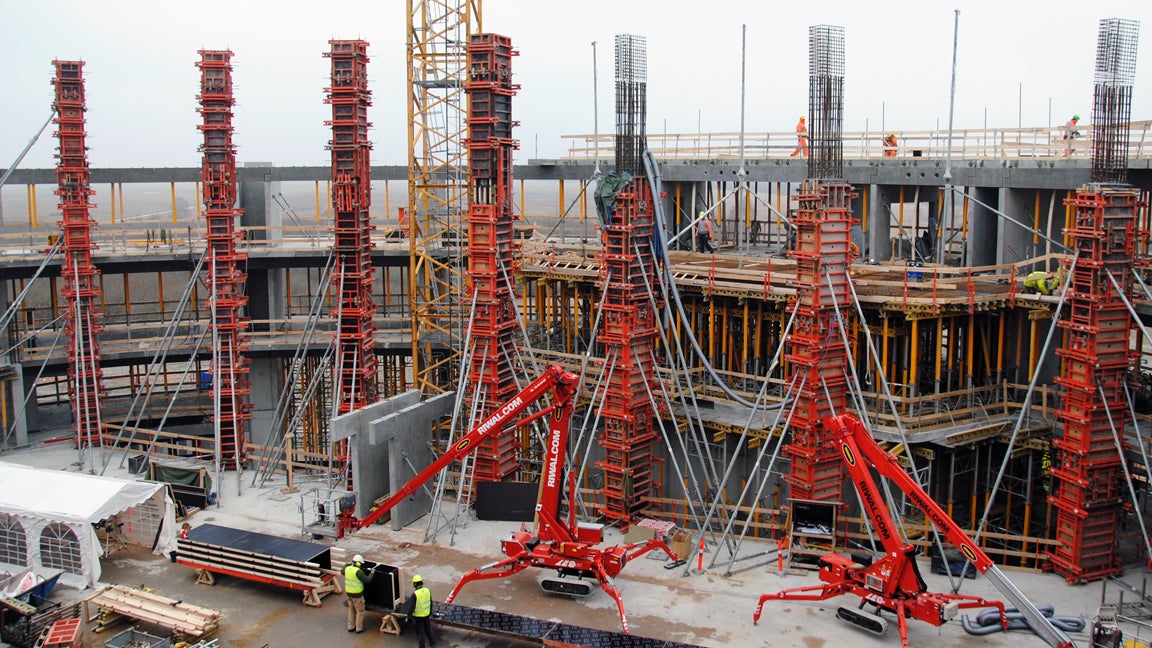 14 m høje søjler i TRIO, som skal have ens finér aftryk.<br/>I baggrunden ses dækstøbningerne hvor der benyttes MULTIFLEX til at føre lasterne til terrændæk.<br/>Herudover MULTIPROPPER hele vejen rundt som understøtning af diverse betondæk.