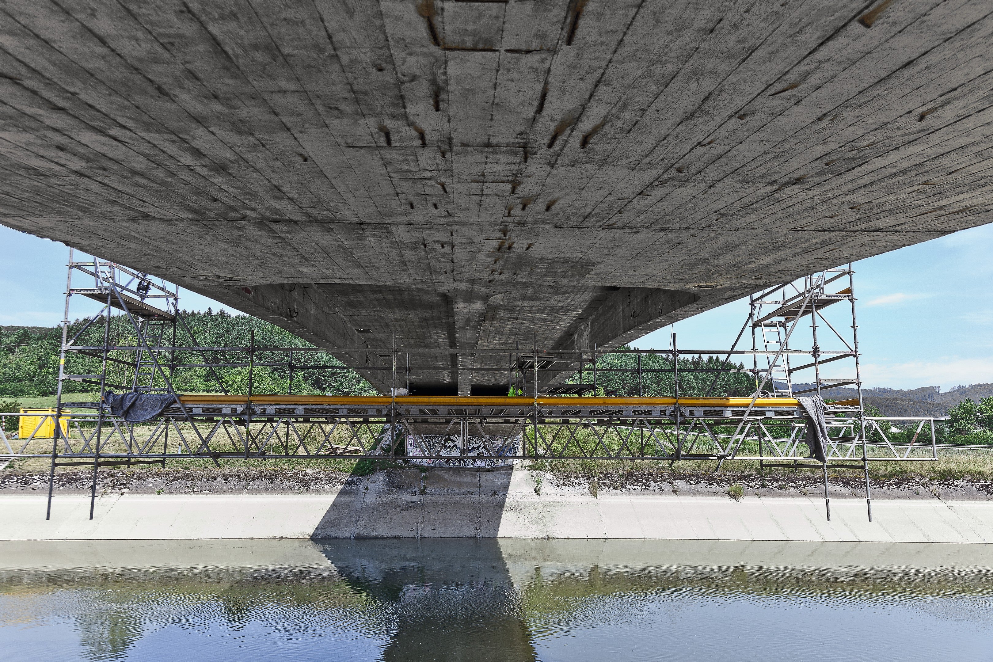 Aby sa pracovníci dostali k spodnej strane mosta, na dolnú časť zavesenej konštrukcie z Rosettu bola zmontovaná a pripevnená pracovná podlaha zo systémov PERI UP Flex a Rosett s rozmermi 12,50 m x 3 m.