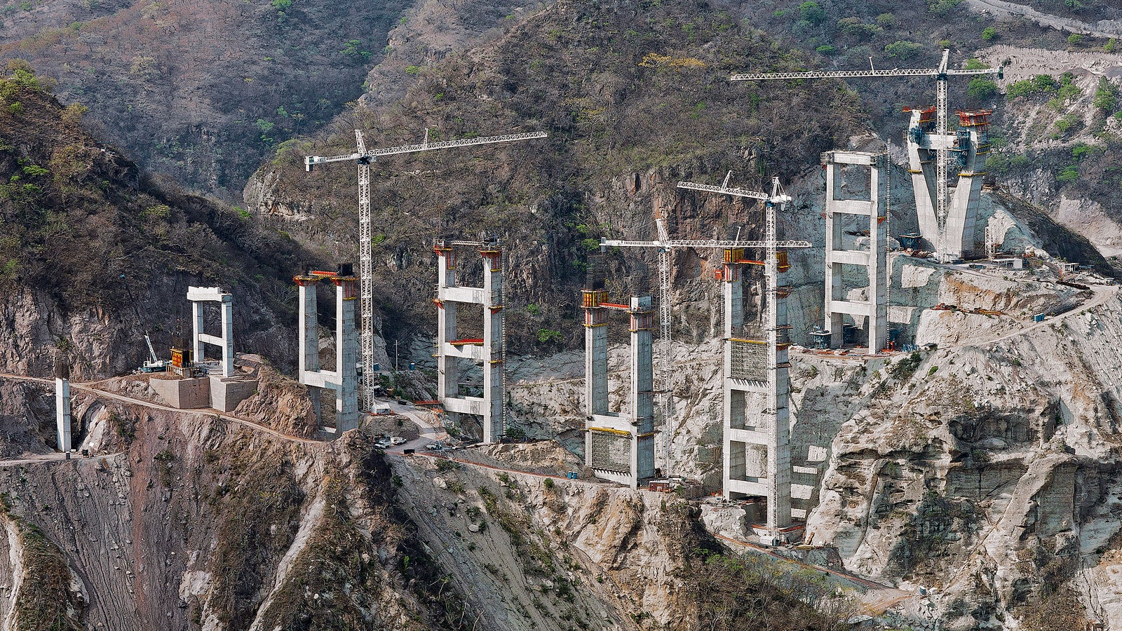 除了两个桥塔结构，在峡谷两侧还浇筑了总共9个双支腿桥墩，中间由大型横梁加固连接。